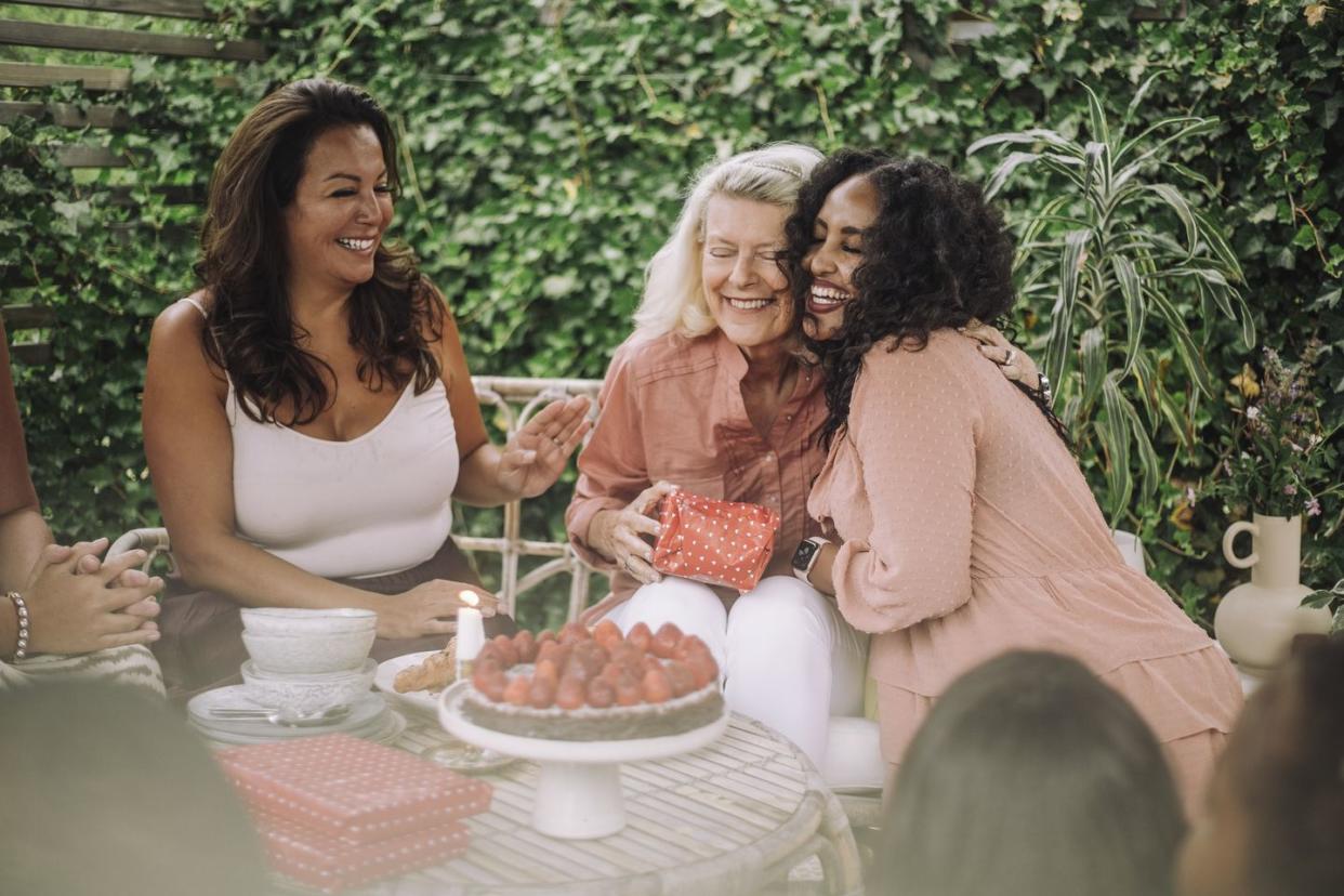 smiling daughter embracing mother in birthday party