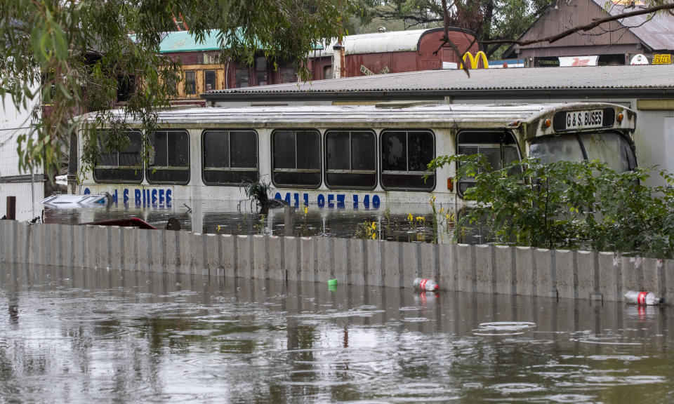 A bus lies partly submerged at a property in Londonderry on the outskirts of Sydney, Australia, Tuesday, March 23, 2021. Hundreds of people have been rescued from floodwaters that have isolated dozens of towns in Australia's most populous state of New South Wales and forced thousands to evacuate their homes as record rain continues to inundate the countries east coast. (AP Photo/Mark Baker)