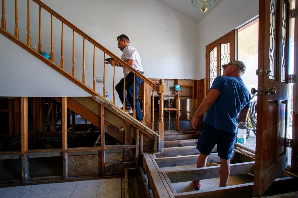 Juan Carlos, right, a subcontractor with JCS Restoration, assesses the Cathedral City home of Rick Ravanello on Oct. 11.