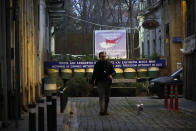 A man walks with his dog in front of barrels and a a painting showing the island in division between the north and south in the capital Nicosia, Cyprus, Friday, Jan. 27, 2023. Cypriots are voting Sunday for a new president who they’ll expect to decisively steer the small island nation through shifting geopolitical sands and uncertain economic times that have become people's overriding concern, eclipsing stalemated efforts to remedy the country’s ethnic division. (AP Photo/Petros Karadjias)