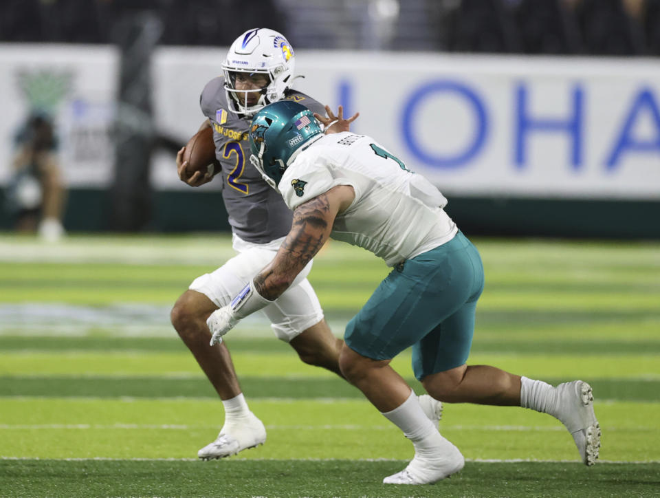 San Jose State quarterback Chevan Cordeiro (2) tries to get away from Coastal Carolina linebacker Shane Bruce (1) during the first half of the Hawaii Bowl NCAA college football game Saturday, Dec. 23, 2023, in Honolulu. (AP Photo/Marco Garcia)