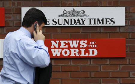 A man passes a sign outside the News International Limited complex, in London January 27, 2011. REUTERS/Suzanne Plunkett