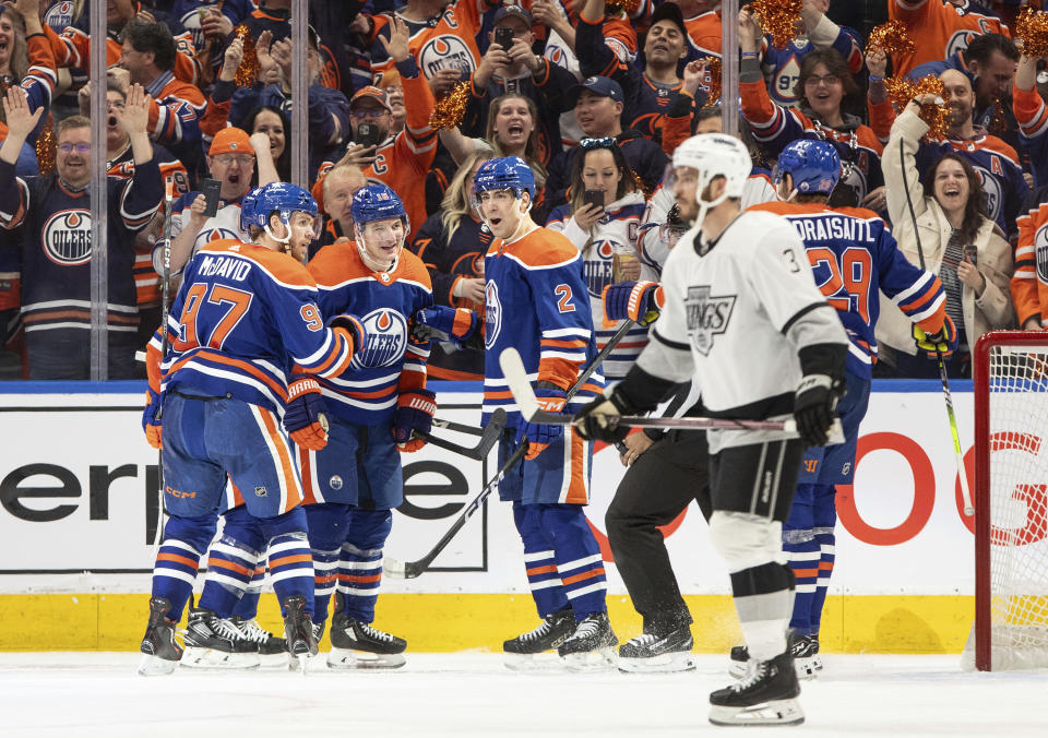 Los Angeles Kings' Matt Roy (3) skates past as Edmonton Oilers' Connor McDavid (97), Zach Hyman (18), Evan Bouchard (2) and Leon Draisaitl (29) as they celebrate a goal during the third period of Game 1 in first-round NHL Stanley Cup playoff hockey action in Edmonton, Alberta, Monday, April 22, 2024. (Jason Franson/The Canadian Press via AP)