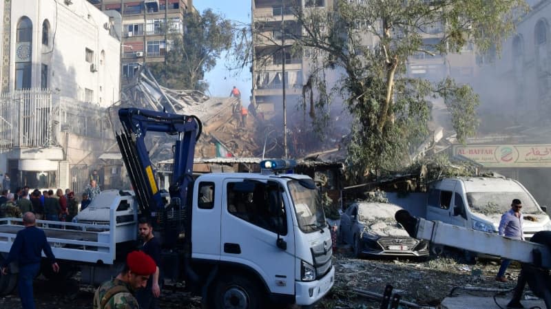 A photo released by the official Syrian Arab news agency (SANA) on 01 April shows people gathering around an Iranian diplomatic destroyed building after a suspected Israeli airstrike. -/SANA/dpa