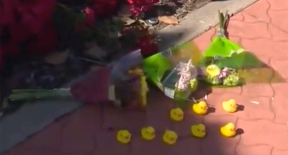 3 bouquet of flowers and 8 yellow rubber ducks can be seen on the ground.