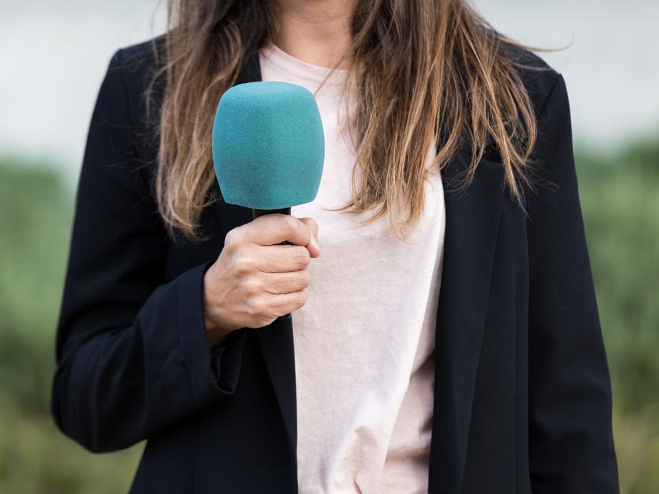 A female journalist holding a microphone