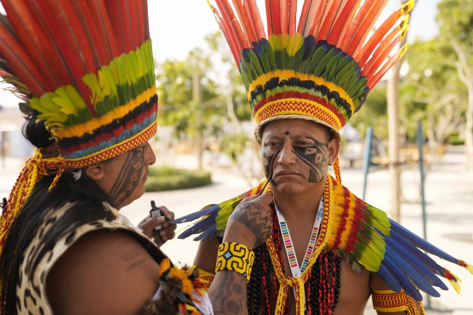 An Indigenous man gets paint on his face at the COP28 U.N. Climate Summit, Saturday, Dec. 9, 2023, in Dubai, United Arab Emirates. (AP Photo/Rafiq Maqbool)