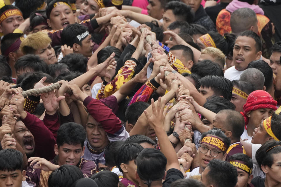 Devotees grab the rope as they pull the glass-covered cart carrying Black Nazarene during its annual procession which was resumed after a three-year suspension due to the coronavirus pandemic on Tuesday, Jan. 9, 2024 in Manila, Philippines. A mammoth crowd of mostly barefoot Catholic devotees joined a chaotic procession through downtown Manila Tuesday to venerate a centuries-old black statue of Jesus Christ with many praying for peace in the Middle East where Filipino relatives work. (AP Photo/Aaron Favila)