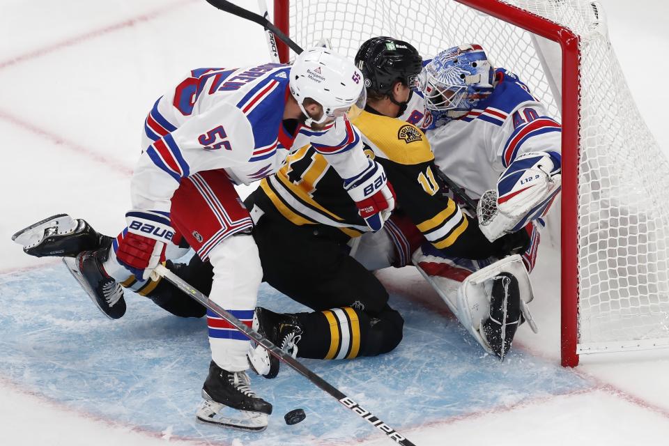 New York Rangers' Ryan Lindgren (55) checks Boston Bruins' Trent Frederic into goalie Alexandar Georgiev (40) during the first period of an NHL preseason hockey game, Saturday, Oct. 2, 2021, in Boston. (AP Photo/Michael Dwyer)
