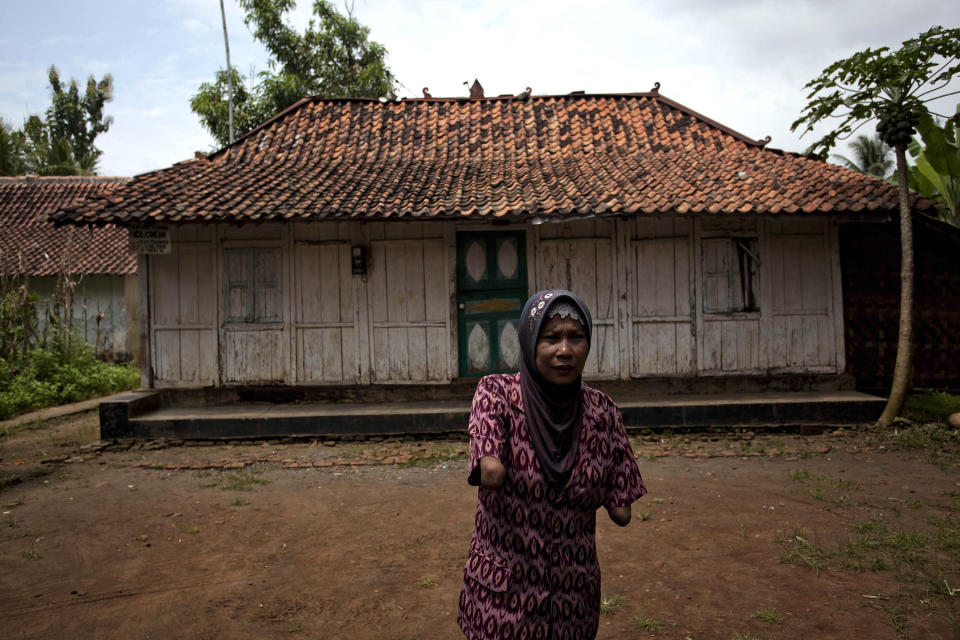 PURWOREJO, INDONESIA - MARCH 13: Armless professional photographer Rusidah, 44, stands outside her house cum studio on March 13, 2012 in Purworejo, Indonesia. Rusidah shoots weddings and parties and has a small studio at home in the village of Botorejo, Bayan District, Purworejo, Central Java where her husband and son also reside. She has been in the photography business for nearly 20 years. (Photo by Ulet Ifansasti/Getty Images)