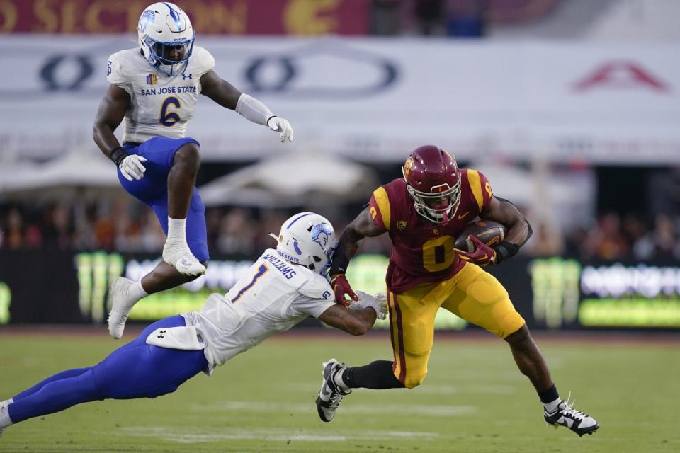 USC running back MarShawn Lloyd carries the ball in front of San José State's Chase Williams and linebacker Bryun Parham.