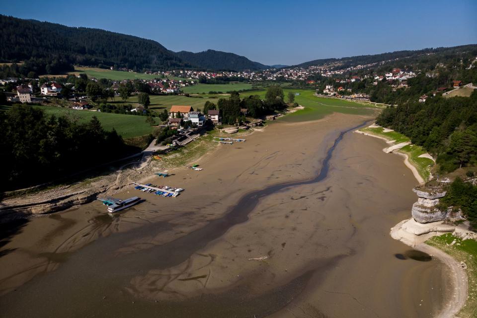 An aerial view shows the dry bed of Brenets Lake (Lac des Brenets), part of the Doubs River, a natural border between eastern France and western Switzerland, in Les Brenets on July 18, 2022. - The river has dried up due to  a combination of factors, including geological faults that drain the river, decreased rainfall and heat waves. (Photo by Fabrice COFFRINI / AFP) (Photo by FABRICE COFFRINI/AFP via Getty Images)