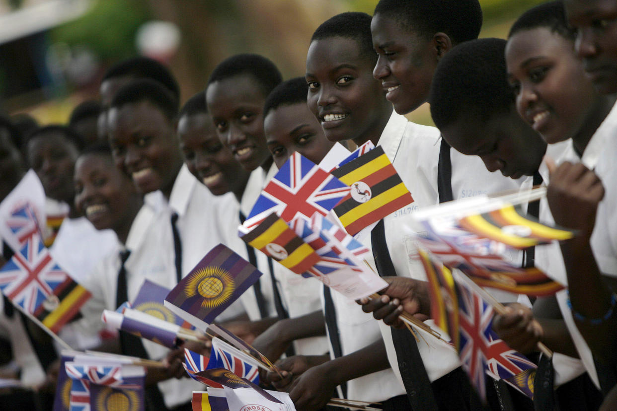 FILE - Ugandan children wave flags to receive Britain's Prince Charles at St. Joseph's School in Naggalama,on the outskirts of Kampala, Uganda, Nov. 24, 2007. When King Charles III is crowned on Saturday, May 6, 2023, soldiers carrying flags from the Bahamas, South Africa, Tuvalu and beyond will be marching alongside British troops to honor King and Country. (Jose Cendon, Pool via AP, File)