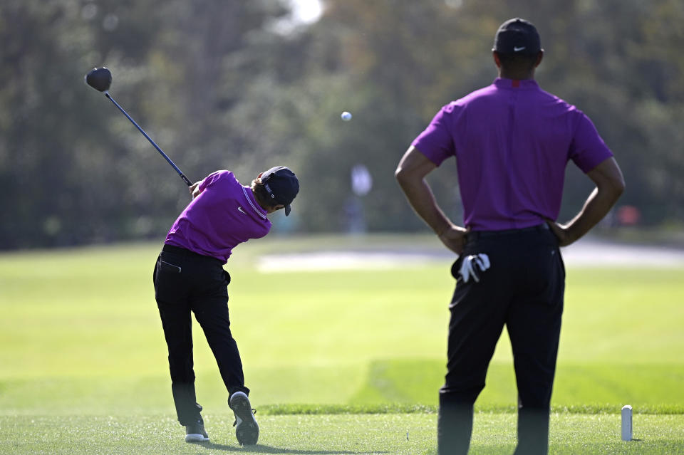 Tiger Woods, right, watches as his son Charlie tees off on the second hole during the first round of the PNC Championship golf tournament, Saturday, Dec. 19, 2020, in Orlando, Fla. (AP Photo/Phelan M. Ebenhack)