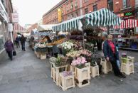 A woman sells flowers at a market stall.