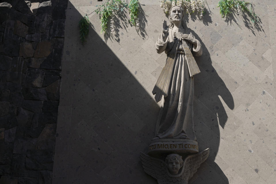 A sculpture of Jesus Christ stands at the entrance of the cemetery in the Mexico City borough of Chilmalhuacan, once the ancient village of Xochiaca, Sunday, July 2, 2023. The traditional stone carvers are dying off and their children generally don’t want to take up the trade. (AP Photo/Aurea Del Rosario)