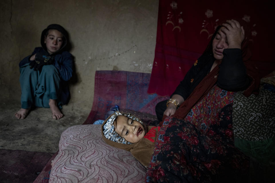 An internally displaced woman takes care of her sick child in a camp on the outskirts of Kabul, Afghanistan, Thursday, Feb. 9, 2023. She has no money to treat her sick child. Since the chaotic Taliban takeover of Kabul on Aug. 15, 2021, an already war-devastated economy once kept alive by international donations alone is now on the verge of collapse. (AP Photo/Ebrahim Noroozi)