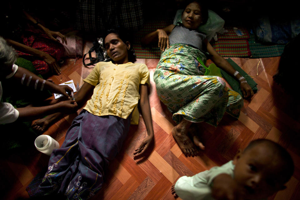 In this Sept. 1, 2012 photo, an HIV-infected woman, center left, gets her medicine through intravenous drips after fainting while another HIV patient is also treated in a hut shared with other HIV-infected patients at an HIV/AIDS center on the outskirts of Yangon, Myanmar. Following a half century of military rule, care for HIV/AIDS patients in Myanmar lags behind other countries. Half of the estimated 240,000 people living with the disease are going without treatment and 18,000 are dying from it every year. (AP Photo/Alexander F. Yuan)