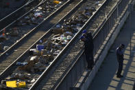 Men look over a railing at a Union Pacific railroad site on Thursday, Jan. 20, 2022, in Los Angeles. Gov. Gavin Newsom on Thursday promised statewide coordination in going after thieves who have been raiding cargo containers aboard trains nearing downtown Los Angeles for months, leaving the tracks blanketed with discarded boxes. (AP Photo/Ashley Landis)