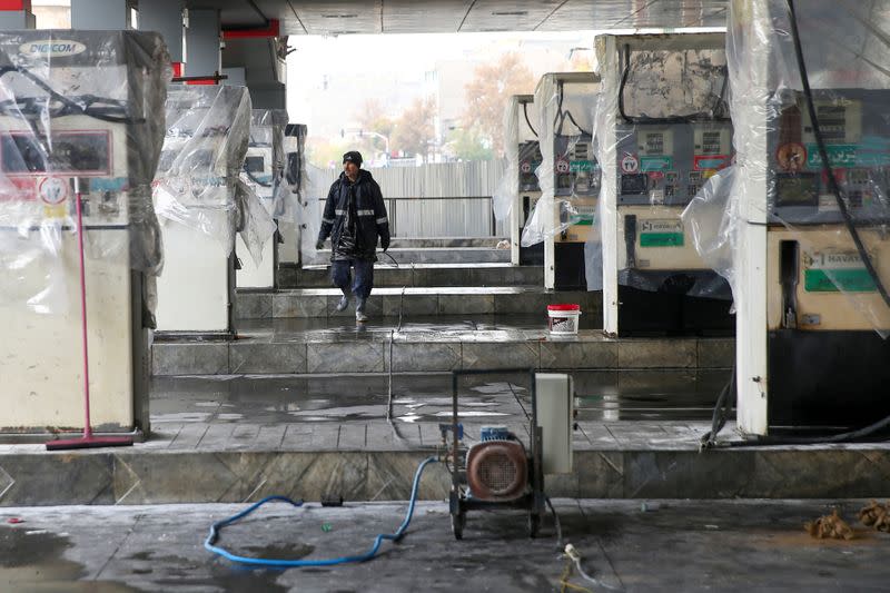 FILE PHOTO: A man walks near the remains of gas pump stands, during protests against increased fuel prices, in Tehran