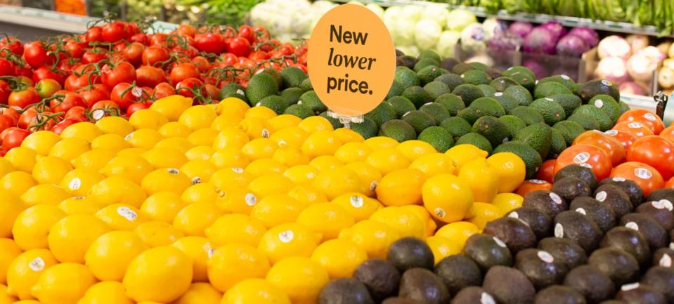 A produce stand with a sign that says "New lower price."