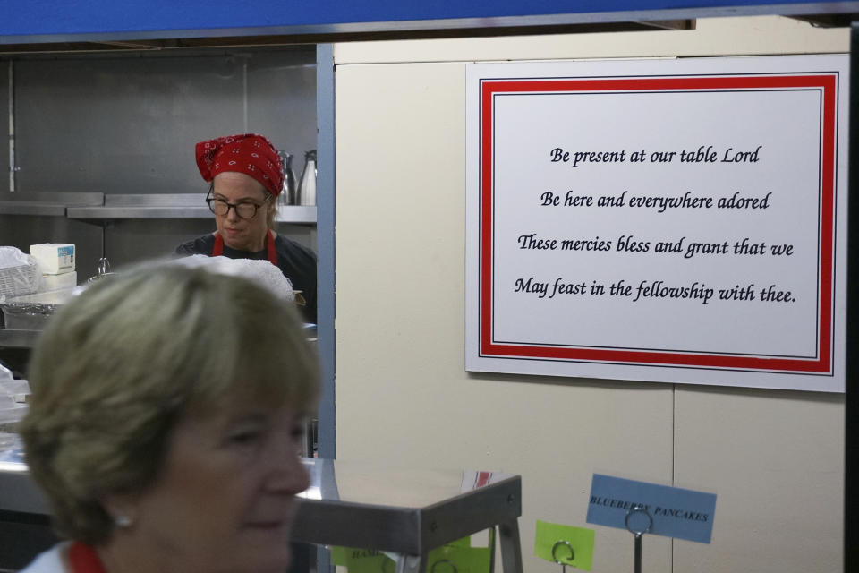 Hamline Church Dining Hall volunteer Sally Johnson walks in front of a prayer sign as she prepares for the breakfast rush on opening day of the Minnesota State Fair in Falcon Heights, Minn., on Thursday, Aug. 24, 2023. The Methodist dining hall started in 1897 among dozens, but is one of two church dining halls still operating at the fair. (AP Photo/Giovanna Dell'Orto)