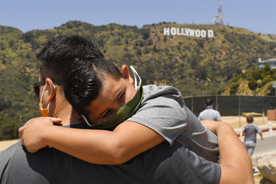 A father and son wait for the Thunderbirds flyover the famed Hollywood sign but were disappointed when they flew several miles south of the sign during the coronavirus outbreak, Friday, May 15, 2020, in Los Angeles. (AP Photo/Mark J. Terrill)