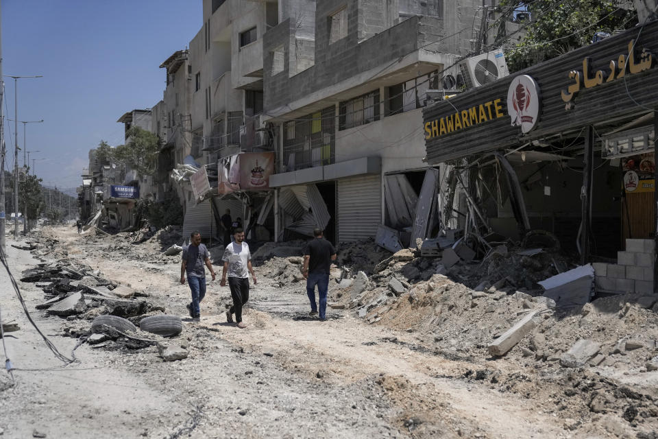 Palestinians walk along a damaged road following an Israeli operation in Nur Shams refugee camp, near the West Bank town of Tulkarem, Monday, July 1, 2024. Palestinian health officials say a woman and a teenager were shot and killed, and four people were wounded by Israeli forces during a raid in the northern West Bank. (AP Photo/Majdi Mohammed)