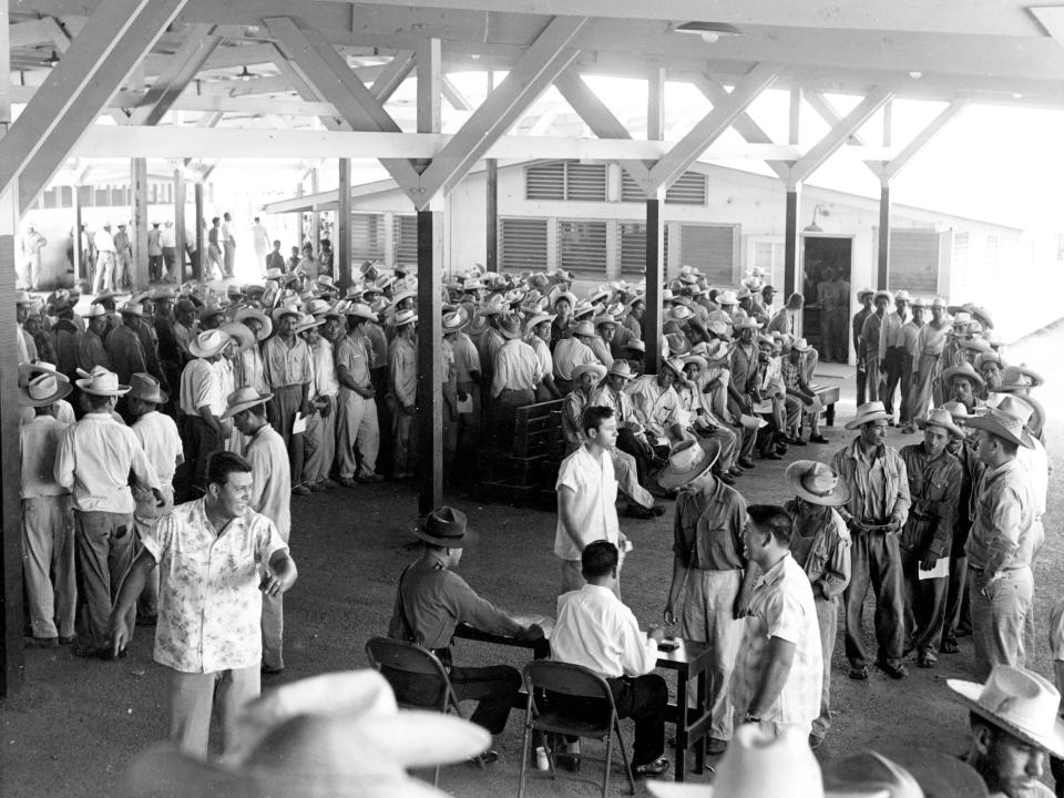 Mexican farm laborers, known as Braceros, line up in a labor center for processing by US immigration officials at the US-Mexico border.