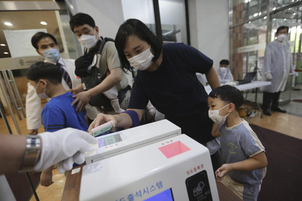 A Christian woman wearing a face mask to help protect against the spread of the new coronavirus scans a QR code on her smartphone before attending a service at the Yoido Full Gospel Church in Seoul, South Korea, Sunday, July 5, 2020. (AP Photo/Ahn Young-joon)