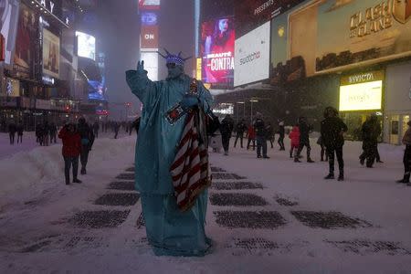 A man is seen posing as the Statue of Liberty during a snow storm in Times Square in the Manhattan borough of New York, January 23, 2016. REUTERS/Carlo Allegri