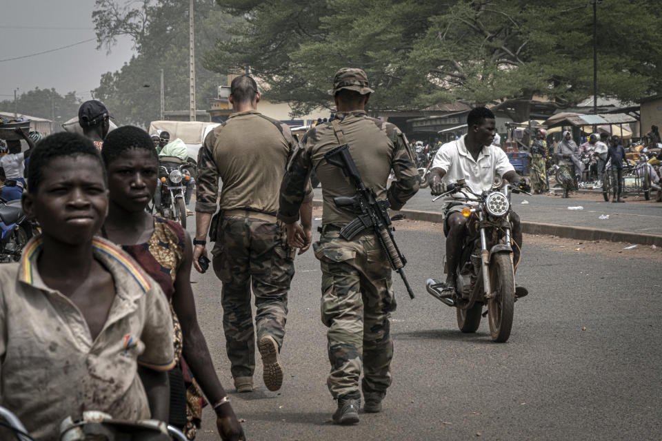 FILE - French army military instructors walk on one of the main roads in Tanguietan, northern Benin, March 28, 2022. Groups linked to al-Qaida and the Islamic State have been spreading from the vast, arid expanse south of the Sahara Desert into wealthier nations on the coast of West Africa. The jihadis' activity in Benin is concentrated in the north of the country, and people there live in constant fear because of the jihadi threat. (AP Photo/ Marco Simoncelli, File)