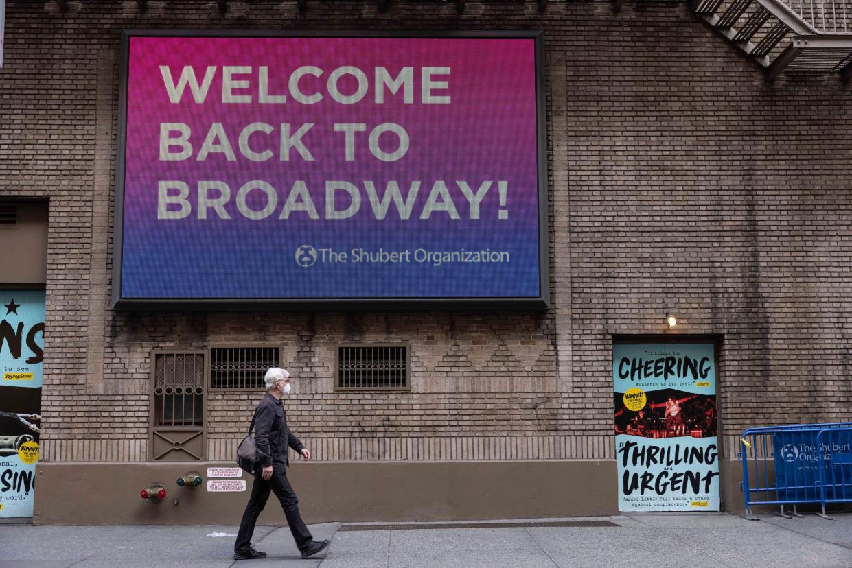 People walk a electronic board reading "Welcome Back to Broadway!" after cancellations of the broadway shows due to COVID-19 cases on Friday, Dec. 17, in New York. 