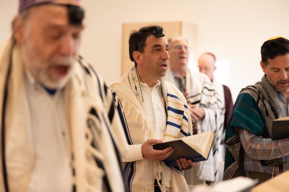 Santa Clara County Dist. Atty. Jeff Rosen, center, reads from the siddur, a prayer book.