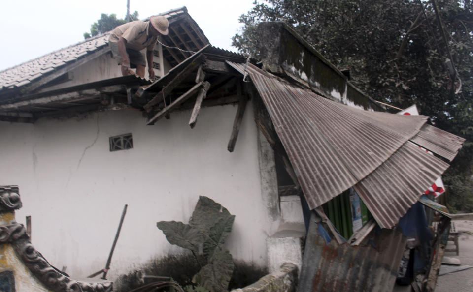 A man cleans a roof covered with volcanic ash from an eruption of Mount Kelud in Kediri, East Java, Indonesia, Friday, Feb. 14, 2014. Volcanic ash from a major eruption in Indonesia shrouded a large swath of the country's most densely populated island on Friday, closed three international airports and sent thousands fleeing. (AP Photo)