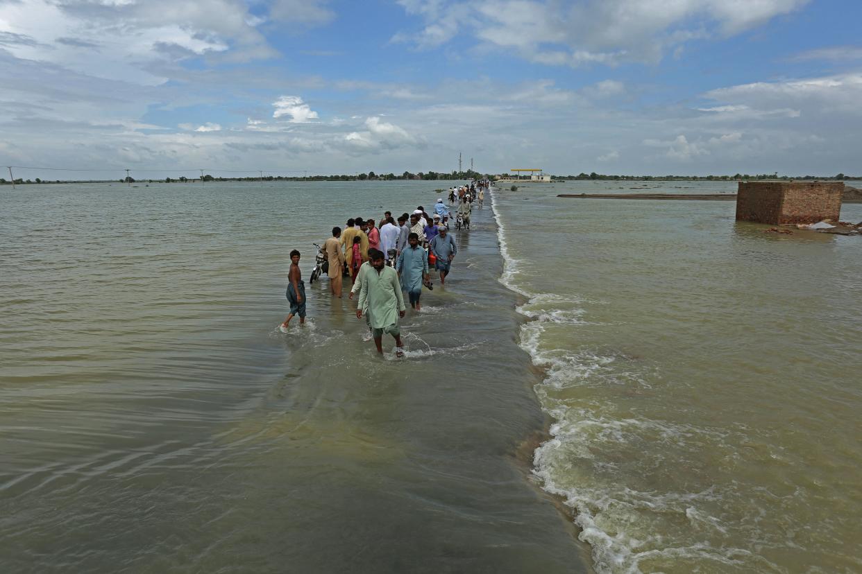 Stranded people wade through a seemingly limitless flooded area in Rajanpur district.