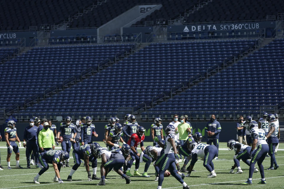 Seattle Seahawks quarterback Russell Wilson, center, waits for the snap during warmups in front of empty seats at CenturyLink Field before an NFL football mock game, Wednesday, Aug. 26, 2020, in Seattle. (AP Photo/Ted S. Warren)