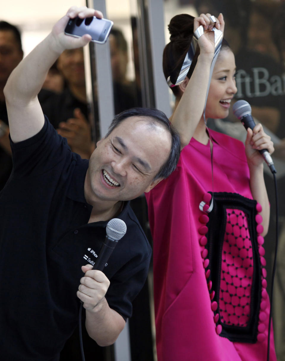 FILE - In this June 26, 2009 file photo, Softbank Corp. President Masayoshi Son, left, and actress Aya Ueto waves to customers waiting the shop to open for the first day sales of iPhone 3GS in Tokyo. The unlikely success story of Son has taken another leap with his latest mega-deal, announced Monday, Oct. 15, 2012 to take a 70 percent stake in U.S. mobile phone carrier Sprint Nextel Corp. for $20 billion. (AP Photo/Junji Kurokawa, File)