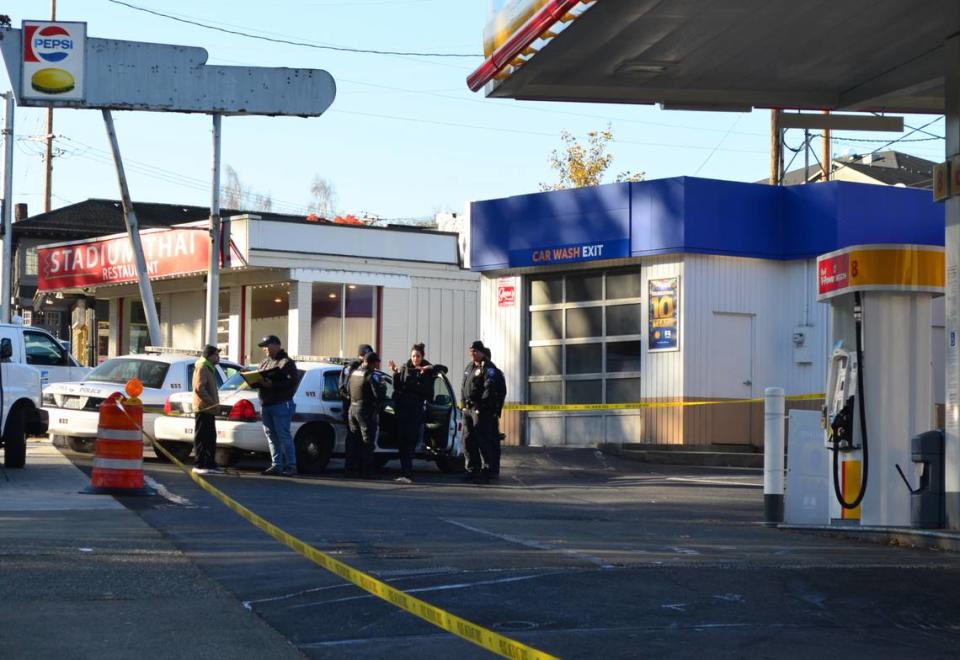 Tacoma Police Department officers gather at the scene of a fatal shooting in the parking lot of a gas station in the 800 block of Division Avenue. The shooting left one man dead and another seriously injured.