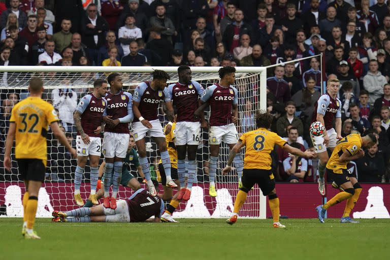 Ruben Neves de Wolverhampton Wanderers ve su tiro libre desviado de Matt Targett de Aston Villa, derecha, para anotar el tercer gol de su equipo durante el partido de fútbol de la Premier League inglesa entre Wolverhampton y Aston Villa