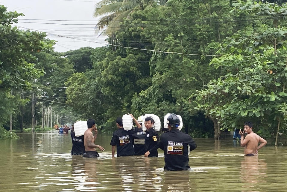 Members of a rescue team carrying food for flood victims wade through a flooded road in Bago, Maynmar, about 80 kilometers (50 miles) northeast of Yangon, Friday, Aug. 11, 2023. (AP Photo)