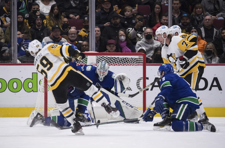 Pittsburgh Penguins' Jake Guentzel, front left, scores his third goal of the night, against Vancouver Canucks goalie Thatcher Demko during the second period of an NHL hockey game Saturday, Dec. 4, 2021, in Vancouver, British Columbia. (Darryl Dyck/The Canadian Press via AP)