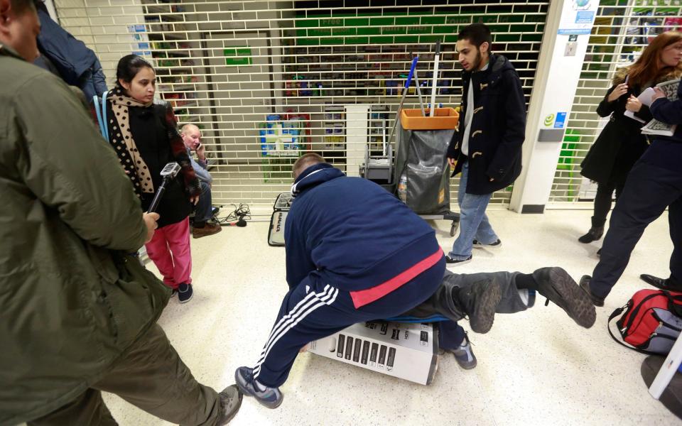 Customers fall to the floor as they grapple for a television during a Black Friday discount sale at an Asda supermarket in 2014