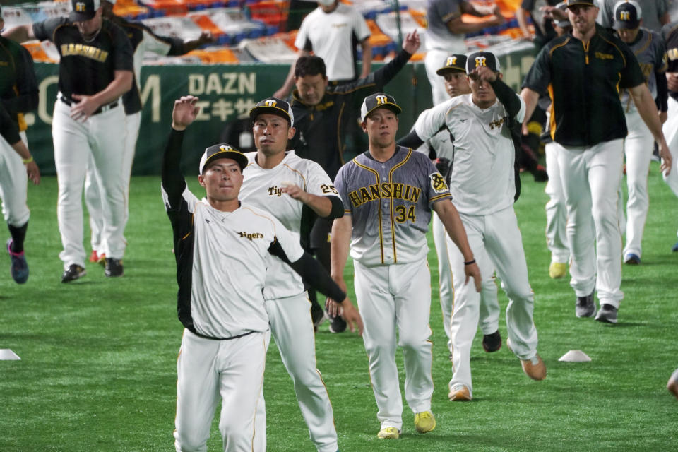 Players of the Hanshin Tigers warm up during a practice session prior to an opening baseball game between the Yomiuri Giants and the Hanshin Tigers at Tokyo Dome in Tokyo Friday, June 19, 2020. Japan's professional baseball regular season will be kicked off Friday without fans in attendance because of the threat of the spreading coronavirus. (AP Photo/Eugene Hoshiko)