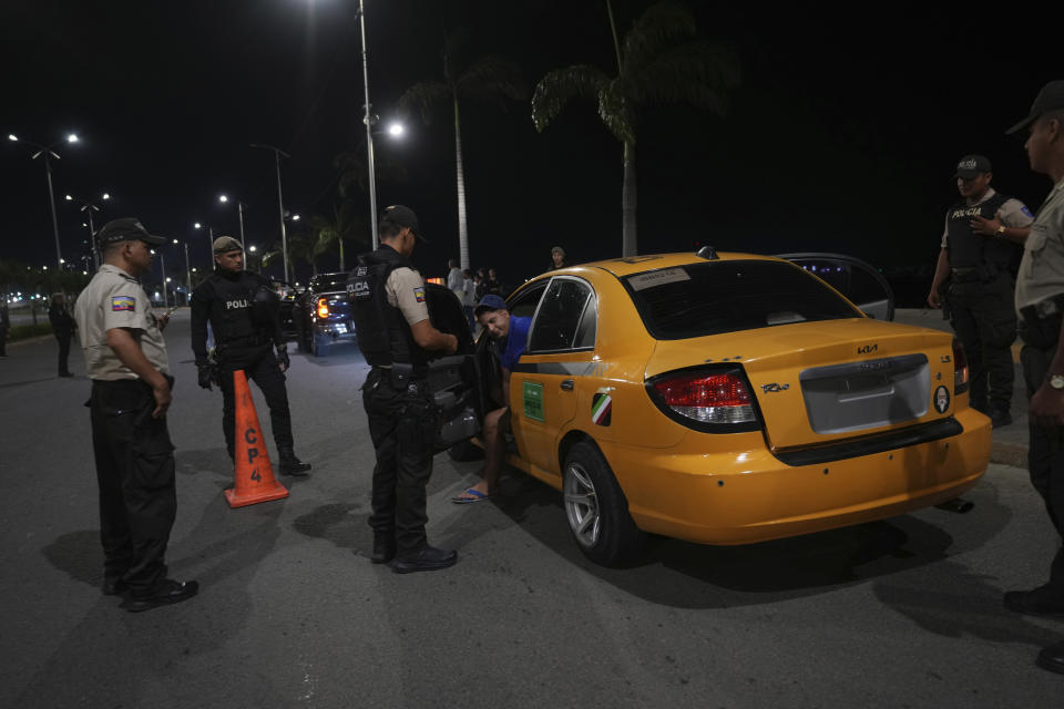 Police check a vehicle and its driver during the start of a curfew decreed by Ecuador´s President Guillermo Lasso to try to reduce the ongoing wave of violence in Manta, Ecuador, Monday, July 24, 2023. (AP Photo/Dolores Ochoa)