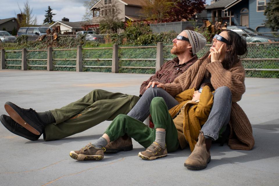 James Holzgraf, left, Yasmina Dedijer-Small and Leif Holzgraf watch the sky during a partial solar eclipse Monday, April 8, 2024, at the College Hill Reservoir in Eugene, Ore.