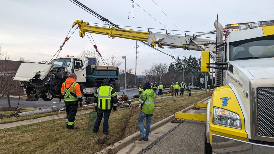 A dump truck is shown being removed after it struck a utility pole at the side of state Route 3030 at Market Square Drive in Streetsboro Tuesday morning, causing power outages in the area.
