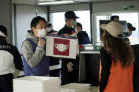 Staffs and security personnel participate in a screening test for spectators and officials to ensure a safe and secure Toyo Olympic Games Wednesday, Oct. 21, 2020, in Tokyo. Tokyo Olympic officials say they don't know exactly what measures will be taken against the COVID-19 pandemic at next year's Games, but they want the world to know they're working on it. (AP Photo/Eugene Hoshiko)