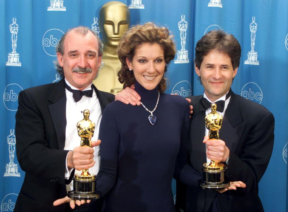 James Horner (R) and Will Jennings (L) hold up their Oscars between Celine Dion after winning for Best Original Song for their work on 