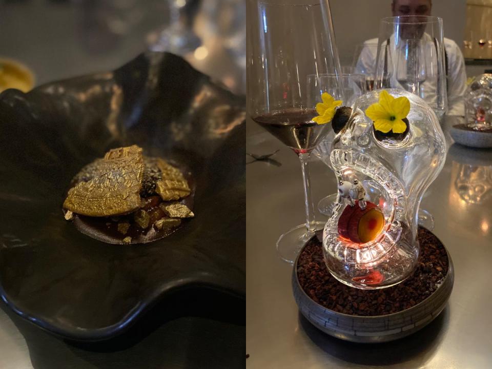 gold-dusted cookie in a bowl next to a glass skull with flowers in its eyes